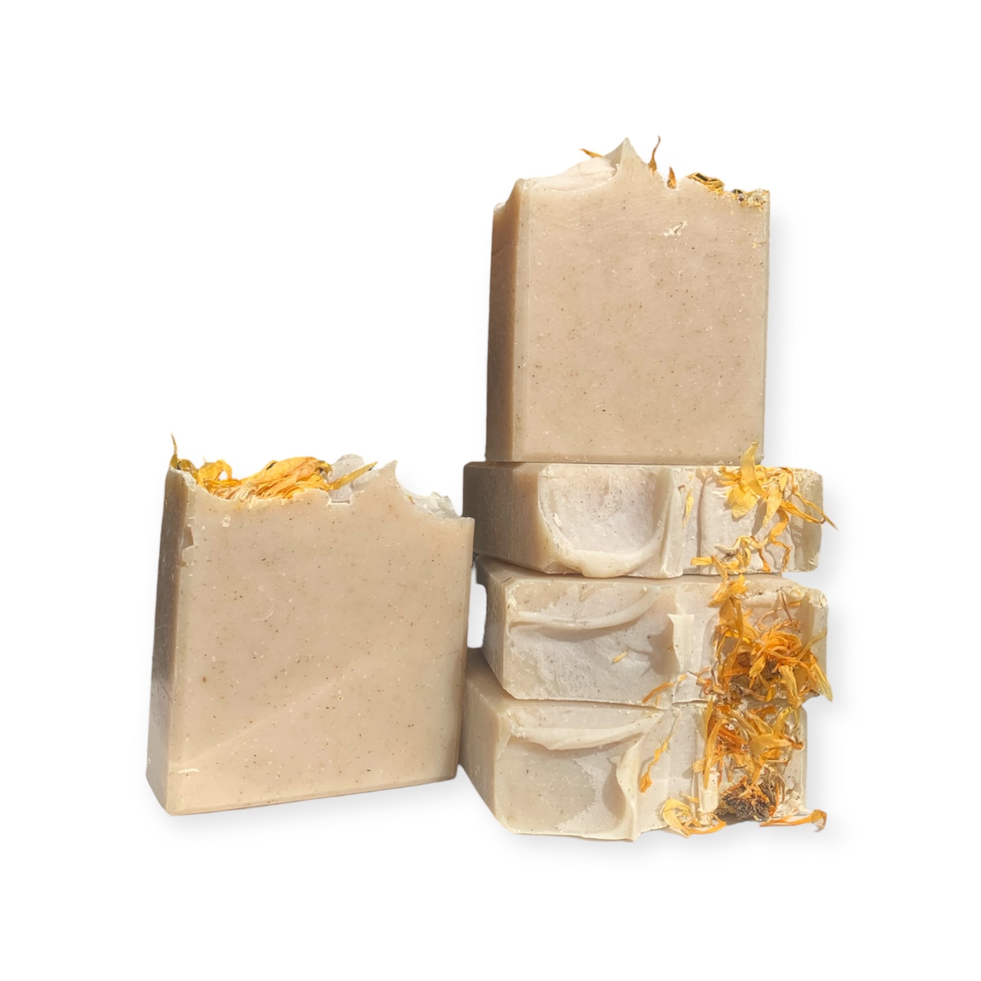 Stack of beige soap bars with calendula flowers on a white background