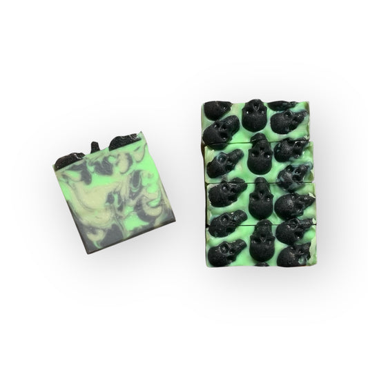Five green  and black soap bars with black skull designs on a white background