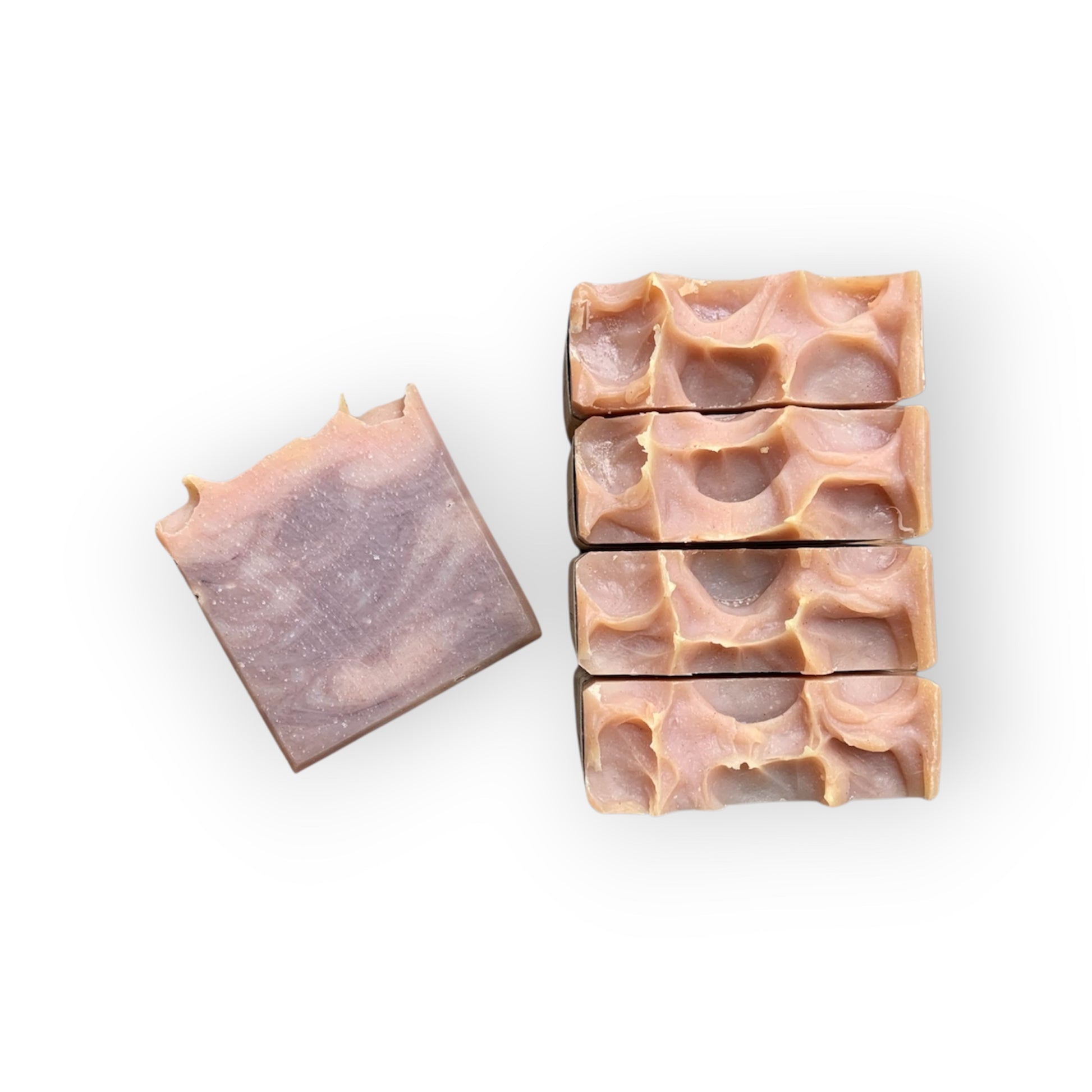 Five bars of pink and burgundy soap with a wavy top on a white background