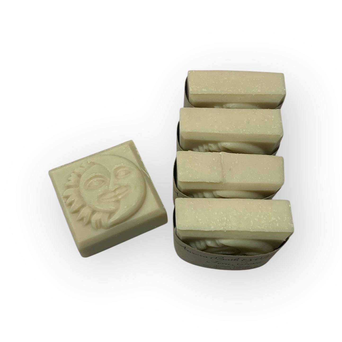 A muted green colored artisan soap with a sun & moon design on top, cut into bars and displayed against a white background.