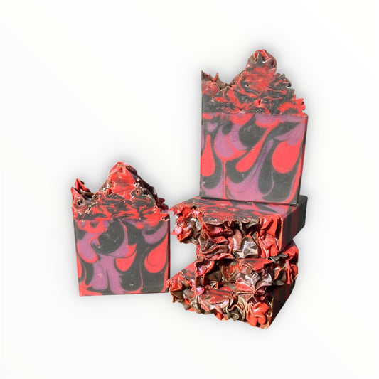 Five handmade soap bars with a marbled swirl pattern of red, black, and purple, arranged on a plain white background.