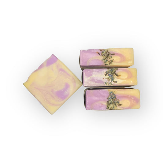 Four soap bars with a purple, white, and yellow marbled design and visible herbs on a white background