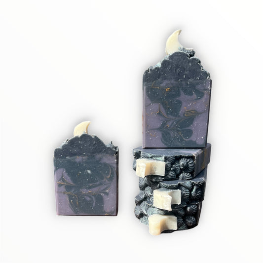 Five decorative soap bars with a dark purple and navy blue swirl design, featuring embedded white moon pieces, shown on a plain white background.