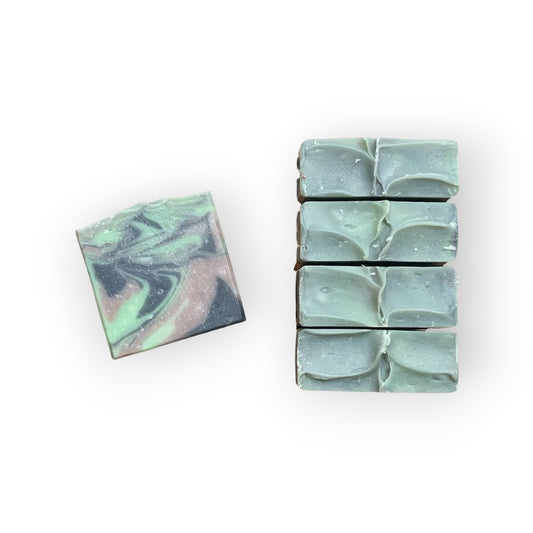 Marble-patterned green, black, and brown soap bars on a white background